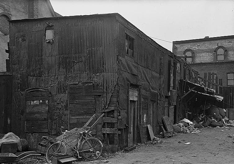 A dilapidated building used as housing at the turn of the century