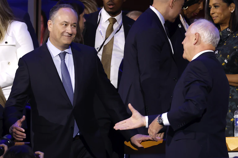 Two men in blue suits about to shake hands.