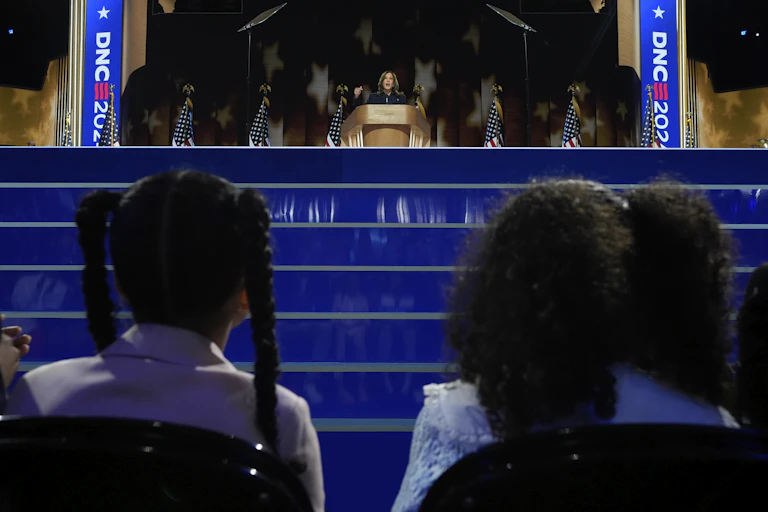 Children watch Kamala Harris speaking on stage at the Democratic National Convention
