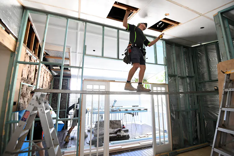 A builder gets up into the roof space during a renovation.