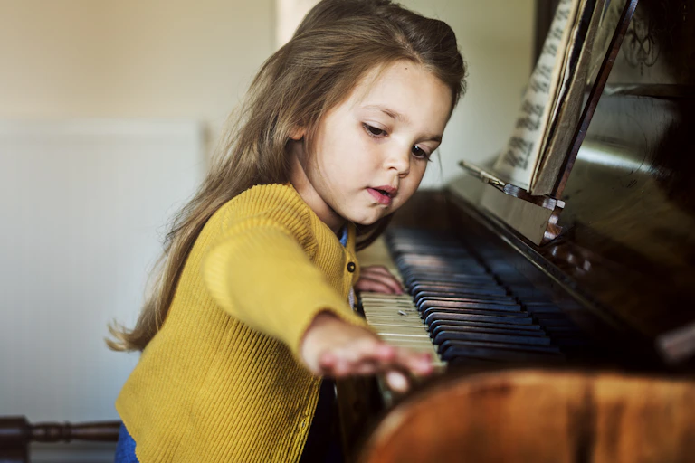 A young girl plays the piano.