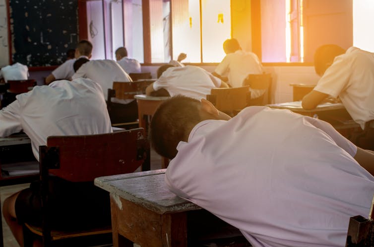 A student lies slumped on his desk.