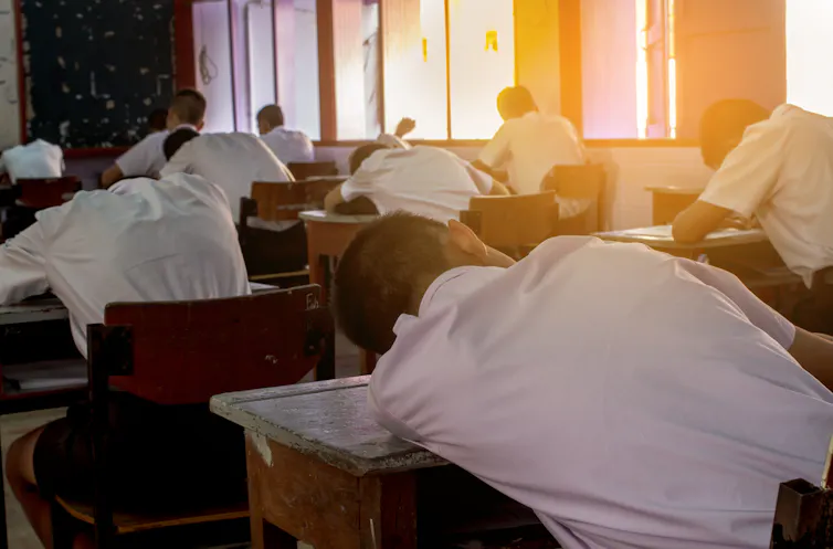 A student lies slumped on his desk.