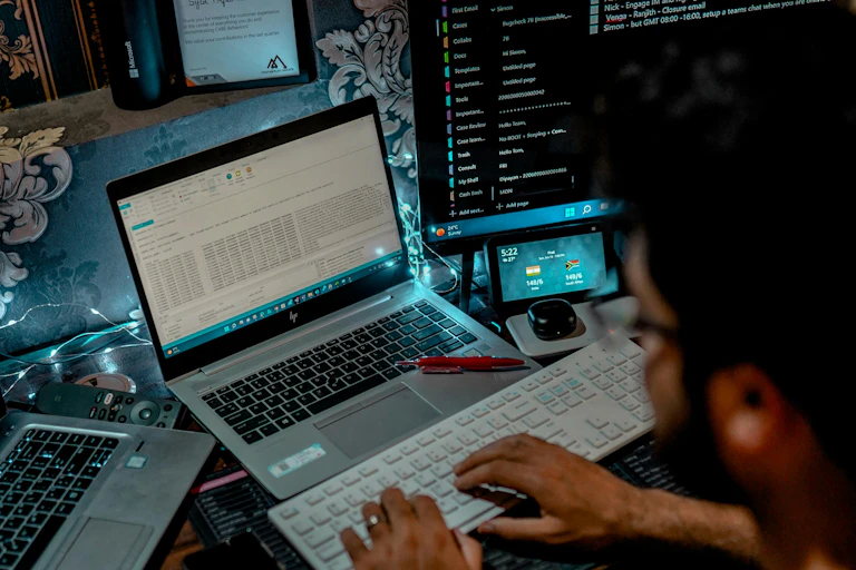 Person sitting in dark room in front of multiple computers