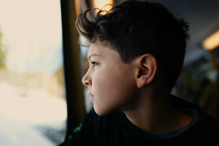 A young teen boy gazes out a window.
