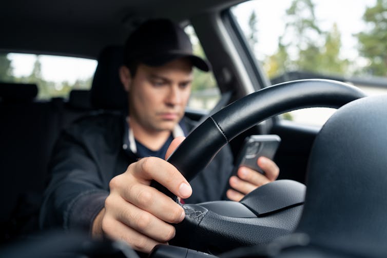 Man looks at his phone while driving.