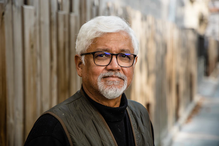 Photo of a bearded man with white hair and spectacles, head and shoulders view