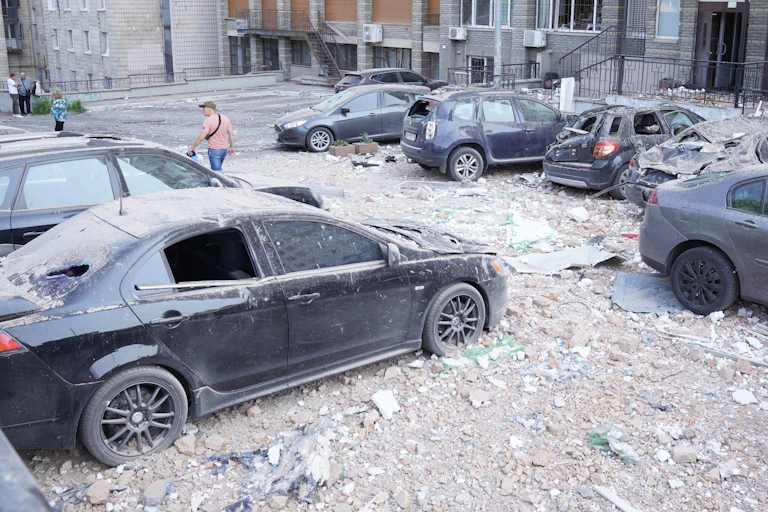 Damaged cars covered in dust, after a drone attack.