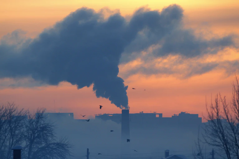 A plume of smoke coming out of a smokestack at a heating plant.