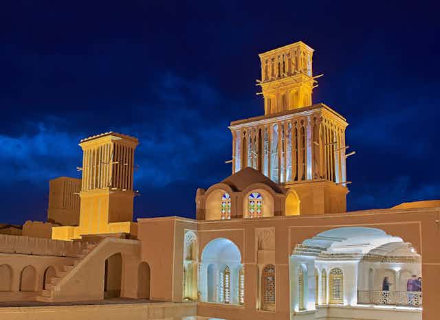 A photo of a historic building with open courtyards and tall towers to capture the wind for cooling.