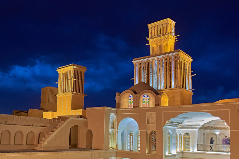 A photo of a historic building with open courtyards and tall towers to capture the wind for cooling.