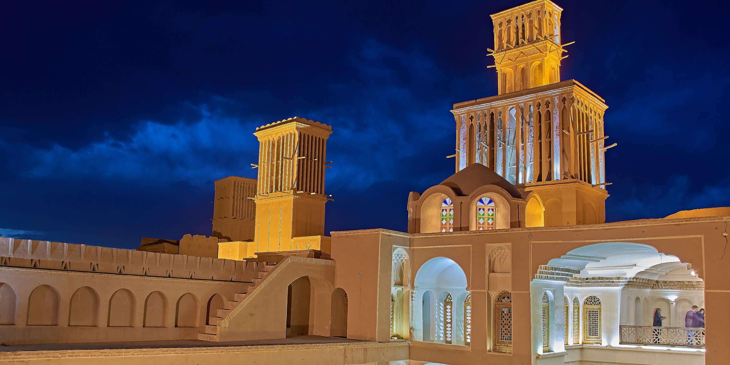 A photo of a historic building with open courtyards and tall towers to capture the wind for cooling.
