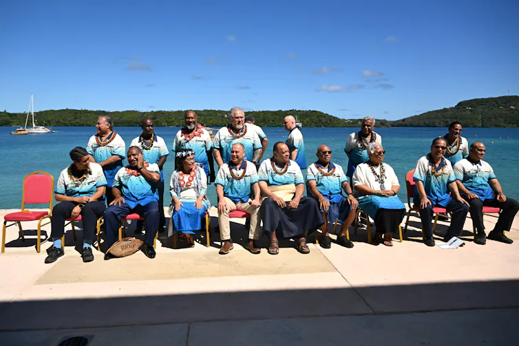 people sitting for photograph in front of ocean