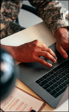 A soldier in office a typing on laptop.