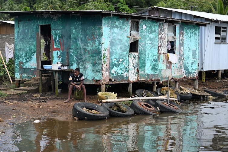village sea level rise, man next to house and rising sea