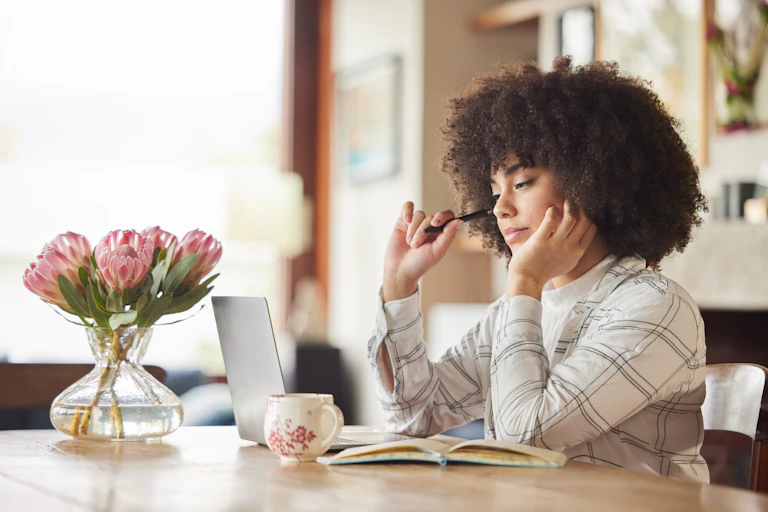 Woman with pen looking at laptop