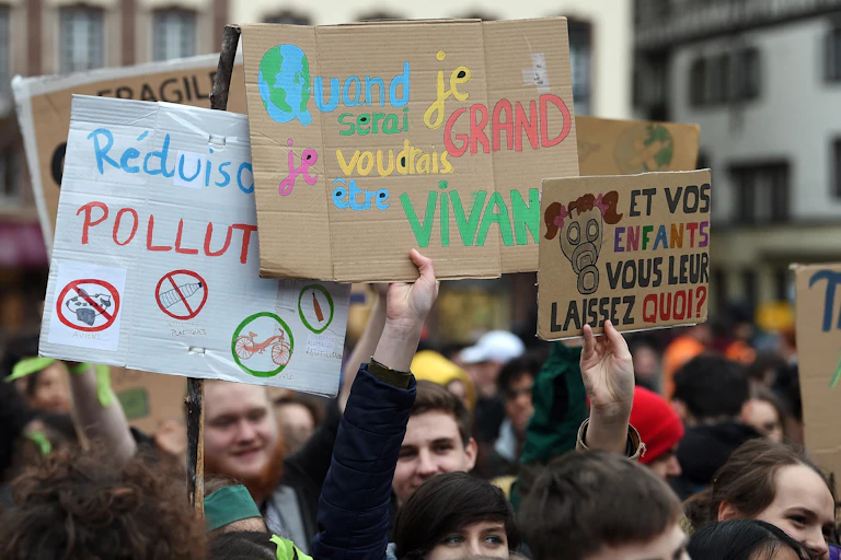 Lors d'une manifestation, des jeunes tiennent des pancartes en lieu avec le dérèglement climatique.