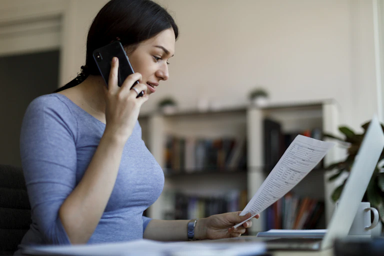 Person holding document in one hand while making a phone call