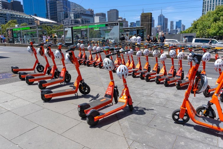 E-scooters lined up on the edge of a wide footpath in Melbourne