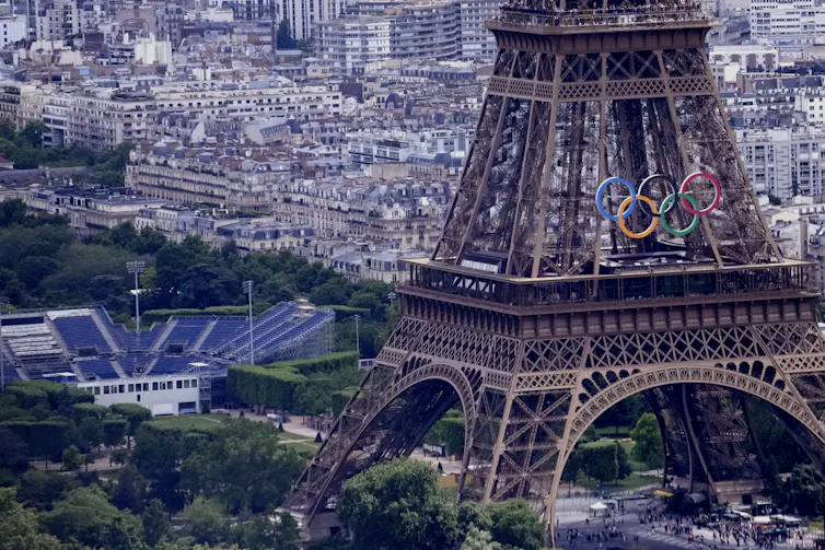 The Olympic rings are seen on the Eiffel Tower in Paris, next to a stadium