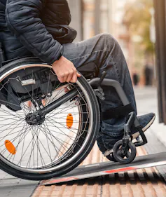 A wheelchair user enters public transport with an accessible ramp.