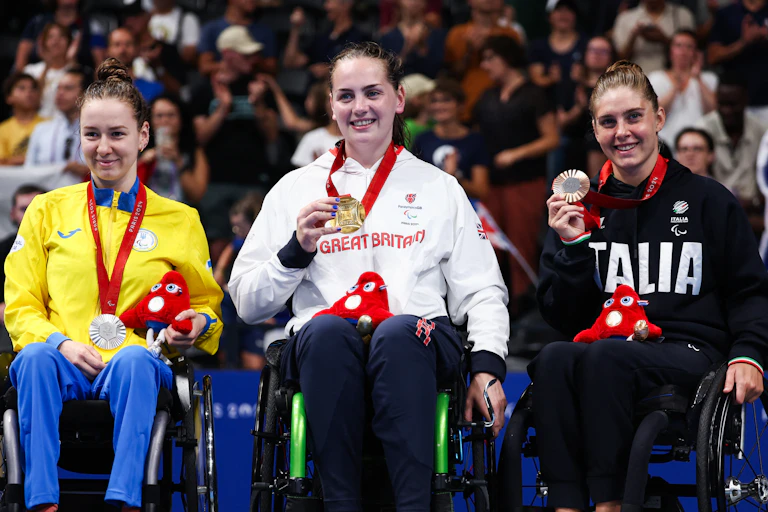 La médaillée d'argent ukrainienne Iryna Poida, la médaillée d'or britannique Tully Kearney et la médaillée de bronze italienne Monica Boggioni célèbrent sur le podium de l'épreuve de natation féminine 200m S5 nage libre lors des Jeux Paralympiques de Paris 2024, le 29 août 2024.