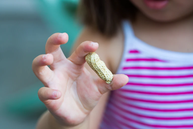 A child holds monkey nuts up to the camera