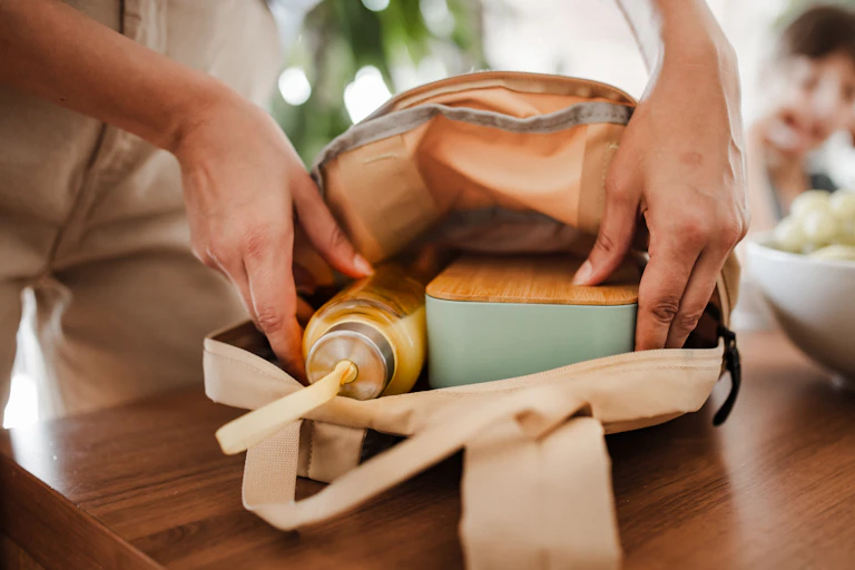 A woman's hands seen putting lunch in a bag.