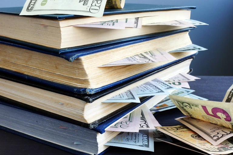 pilha de livros com notas de dólar entre suas páginas