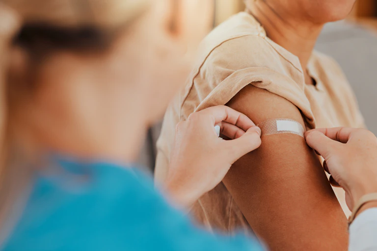 A health-care worker puts a bandaid on a person's arm.