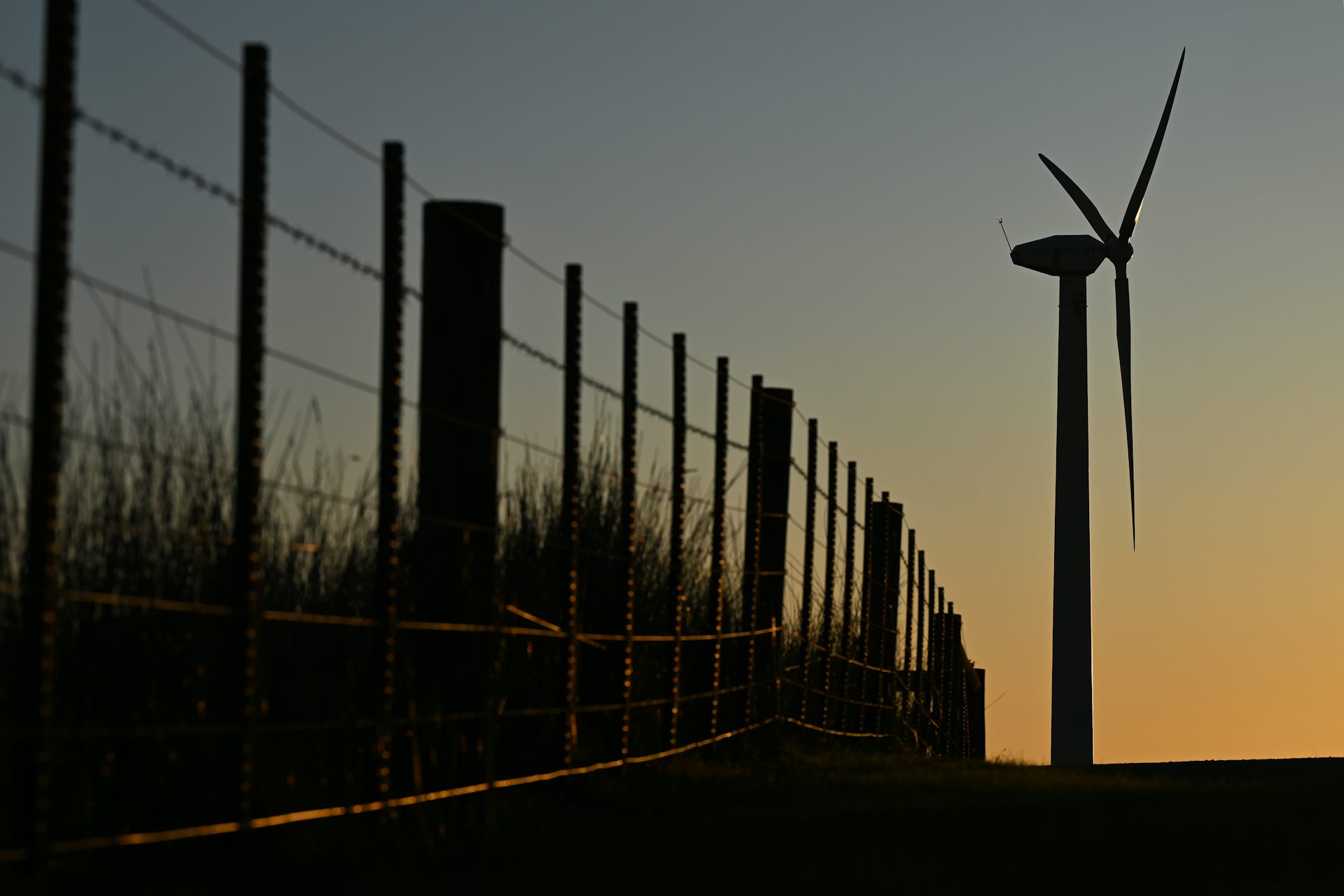 wind turbine and fence at sunset