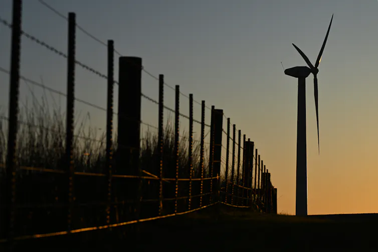 wind turbine and fence at sunset