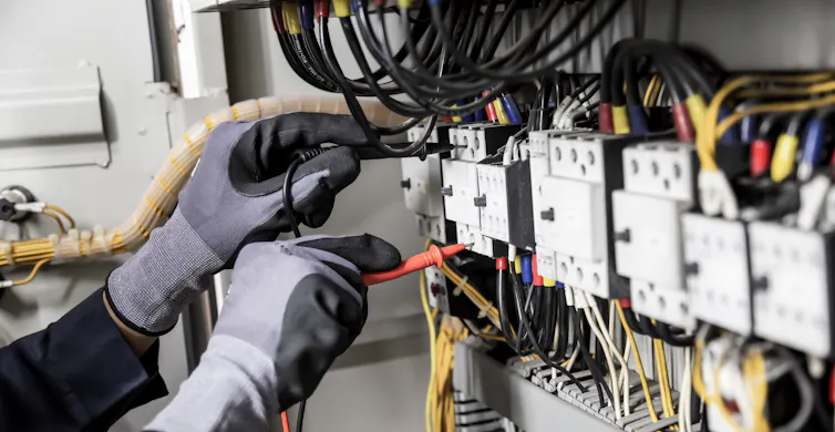 gloved hands tinker with power box