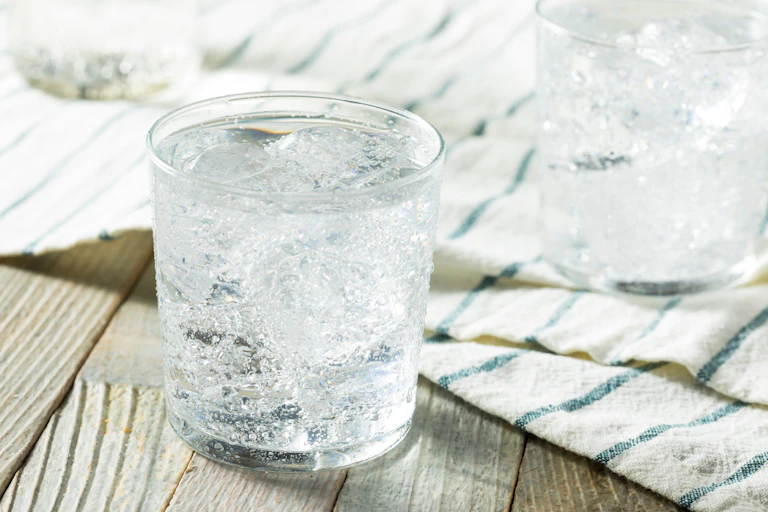 A cold glass of soda water on a wooden table.