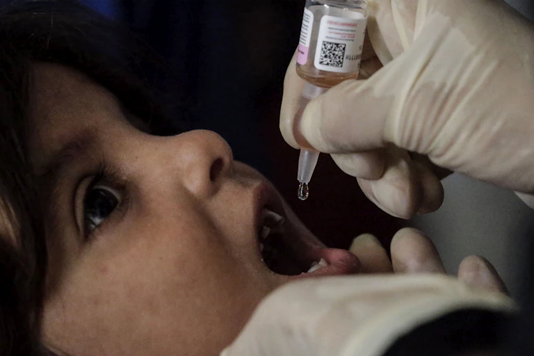 A nurse administers polio vaccine drops to a Palestinian child.