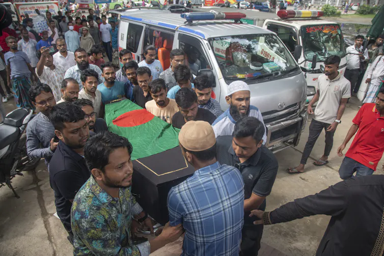 People carry a coffin covered with the Bangladesh national flag.
