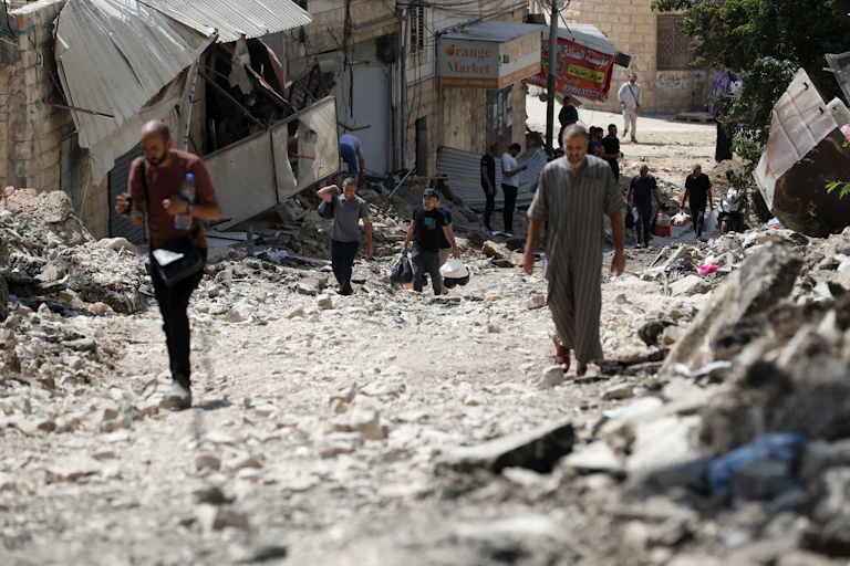 Palestinians inspect the damage on a street.
