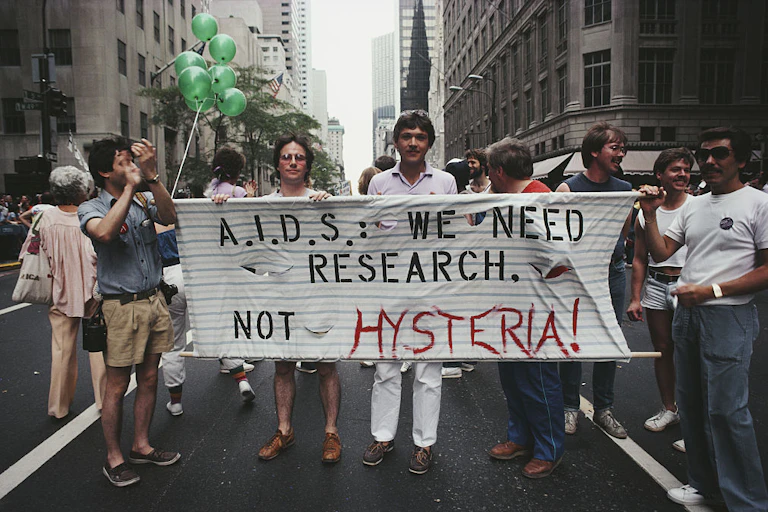 Protesters carry a sign that says, 'A.I.D.S: We need research, not hysteria!'