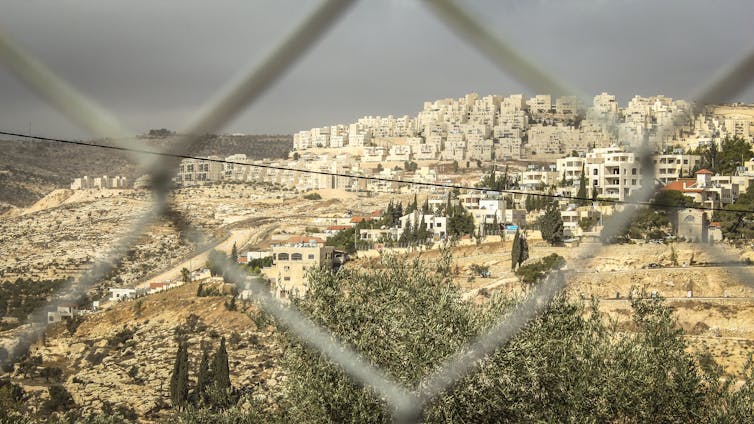 An Israeli settlement in the West Bank viewed through a gap in a fence.