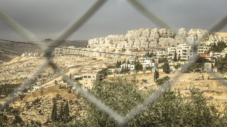 An Israeli settlement in the West Bank viewed through a gap in a fence.