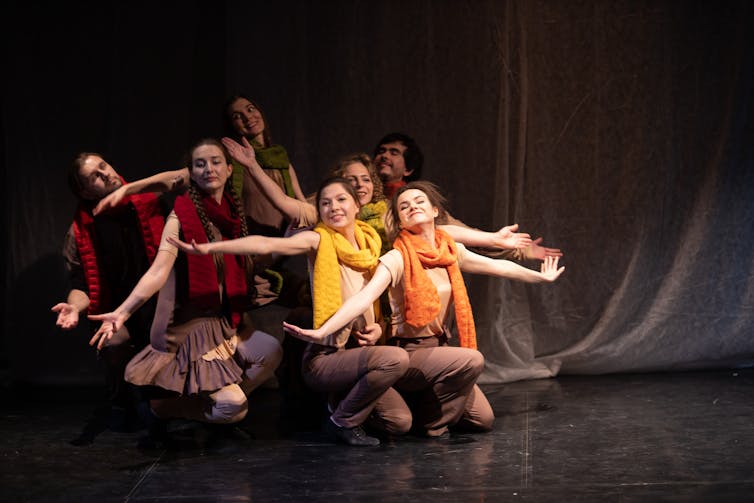 Drama students practise a play on stage while wearing bright costumes.