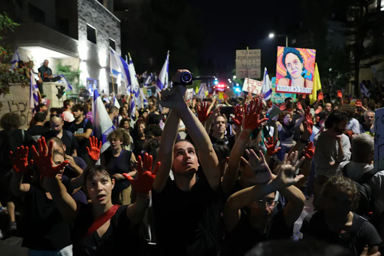 Israeli protesters in a darkened street.