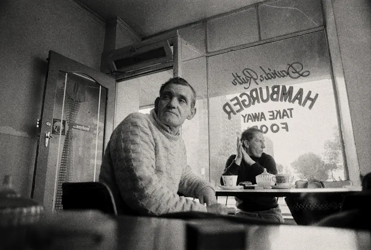 Two old people drink tea in a hamburger joint.