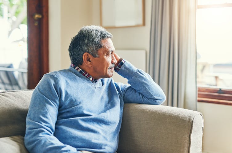 A man sitting on a couch looking out a window.
