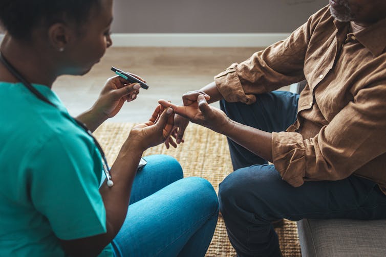 A nurse does a finger prick blood glucose test on a patient.