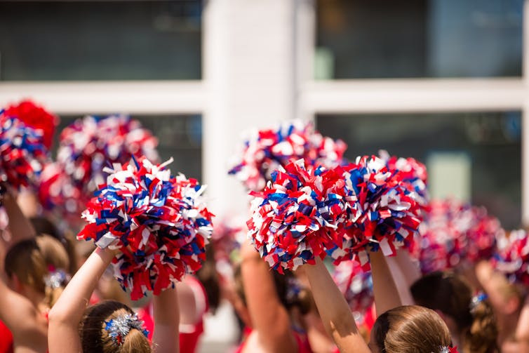 A group of children raise pom poms in the air.