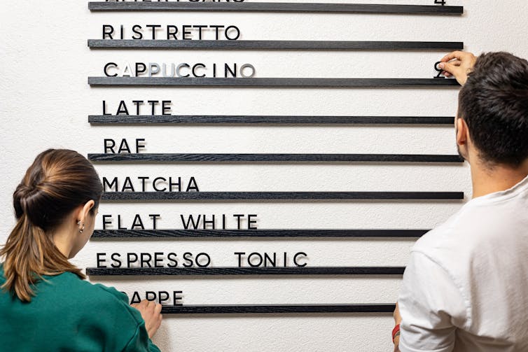 A woman and a man putting letters on a sign