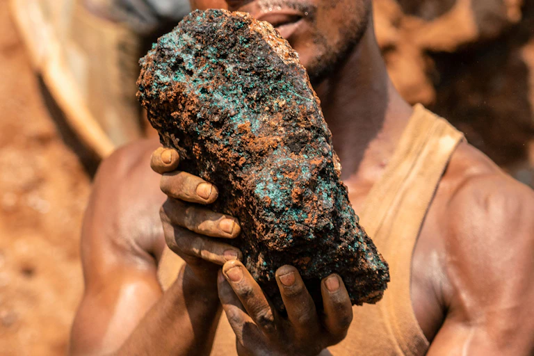 A miner holds up a stone.