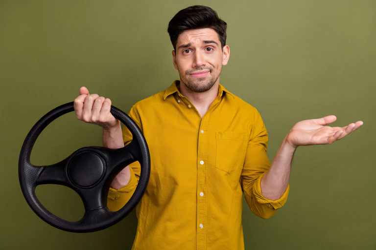 Man holding steering wheel against green background