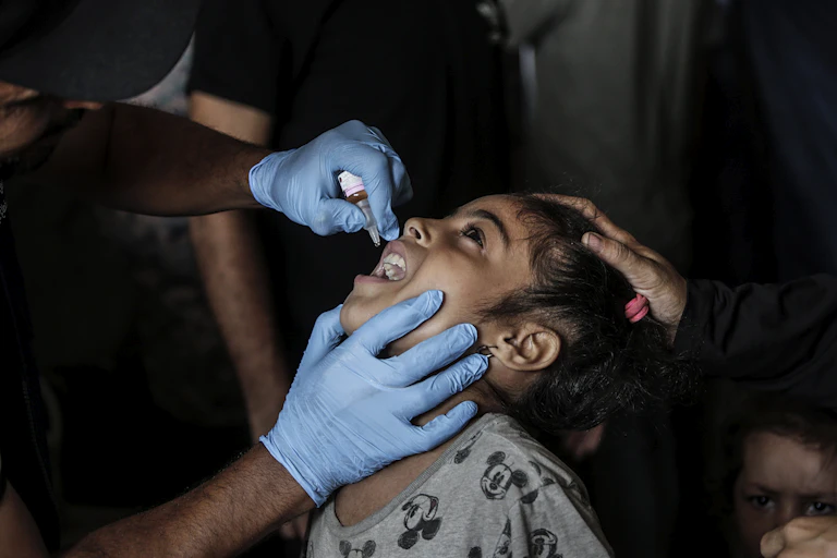 A nurse administers polio vaccine drops to a Palestinian child at at a United Nations school in Deir Al Balah town, southern Gaza Strip